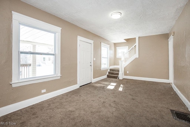 carpeted foyer with plenty of natural light and a textured ceiling