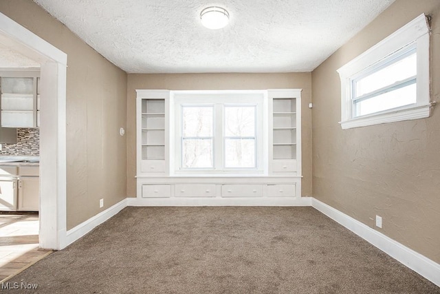 carpeted empty room featuring a textured ceiling