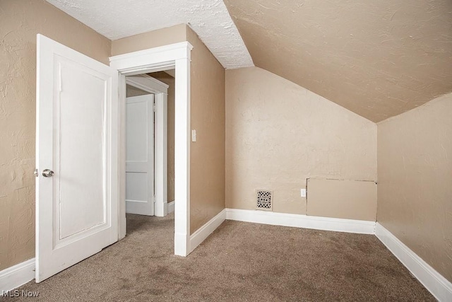 bonus room with vaulted ceiling, carpet flooring, and a textured ceiling