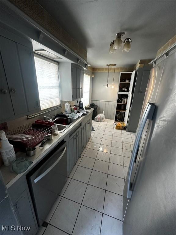 kitchen featuring dishwashing machine, light tile patterned flooring, gray cabinetry, and stainless steel fridge