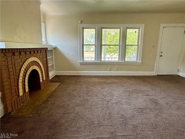 unfurnished living room featuring dark carpet and a brick fireplace