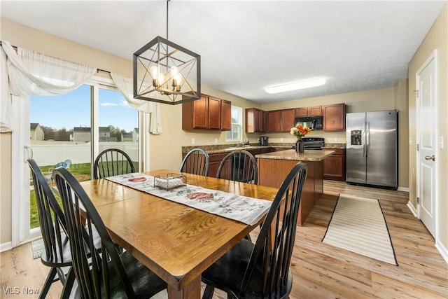 dining room with sink, light hardwood / wood-style flooring, and an inviting chandelier