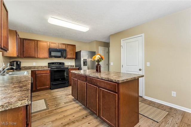 kitchen with sink, black appliances, light wood-type flooring, and a kitchen island