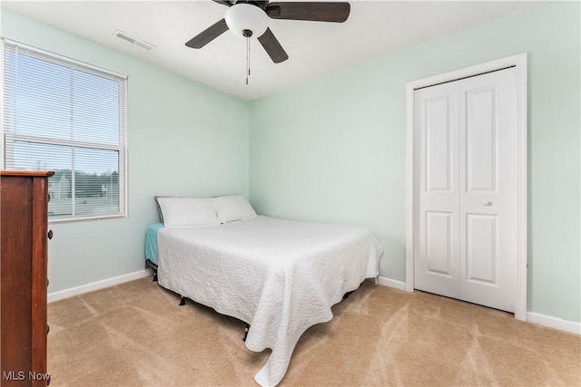 carpeted bedroom featuring ceiling fan and a closet