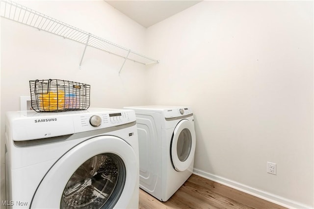 laundry area featuring washing machine and clothes dryer and light hardwood / wood-style floors