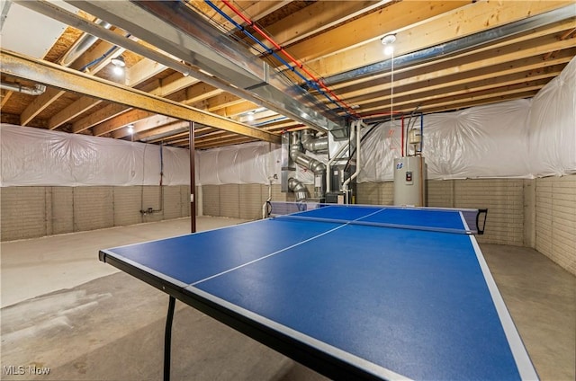 recreation room with concrete floors, water heater, and brick wall