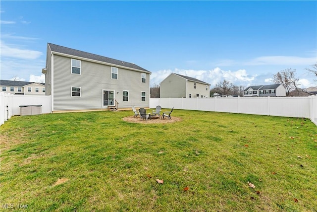 back of house with an outdoor fire pit and a lawn