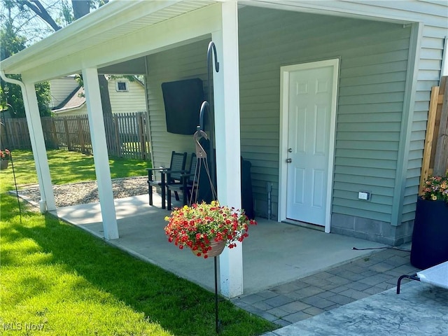 entrance to property featuring a patio area and a yard