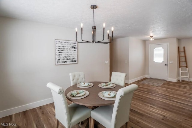 dining area with dark wood-type flooring, a textured ceiling, and a notable chandelier