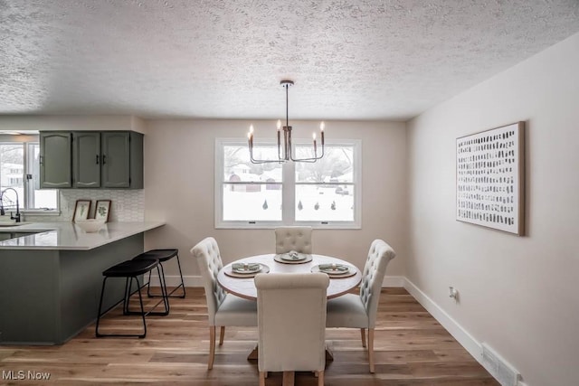 dining room with sink, hardwood / wood-style floors, a textured ceiling, and a chandelier