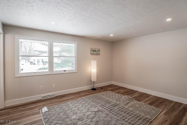 spare room featuring dark wood-type flooring and a textured ceiling