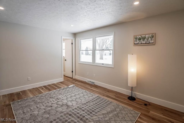 spare room featuring wood-type flooring and a textured ceiling