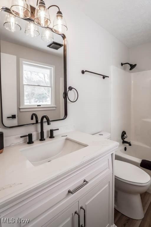 full bathroom featuring hardwood / wood-style floors, washtub / shower combination, vanity, and toilet