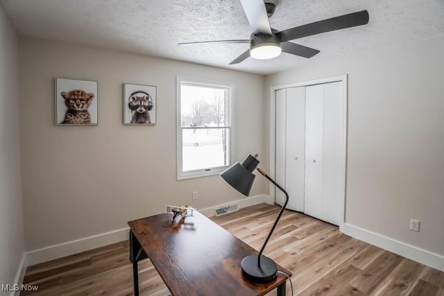 office space featuring hardwood / wood-style flooring, ceiling fan, and a textured ceiling