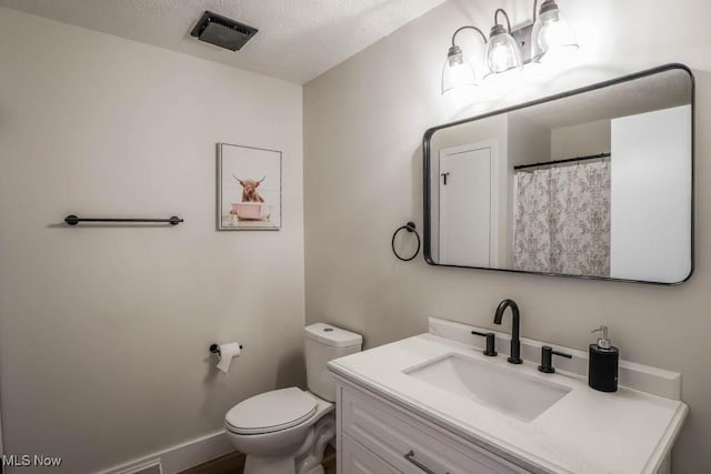 bathroom featuring toilet, a textured ceiling, and vanity