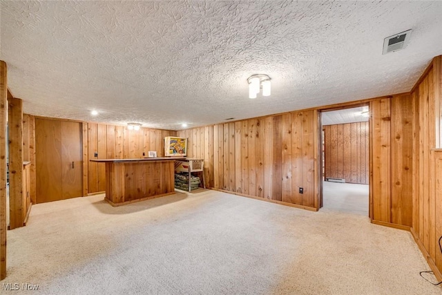 bar with wood walls, a textured ceiling, and light carpet