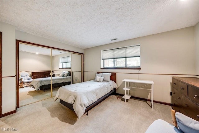 bedroom featuring light colored carpet, a textured ceiling, and a closet