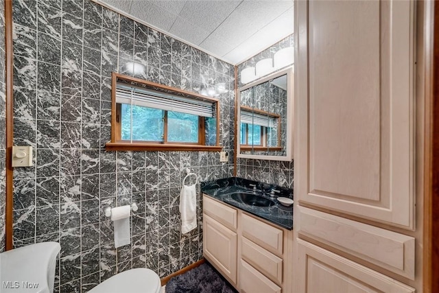 bathroom with toilet, vanity, and tile walls