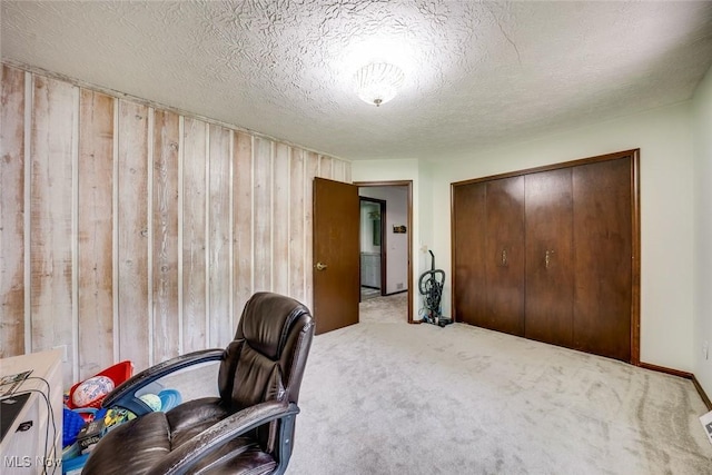 office with a textured ceiling, carpet flooring, and wooden walls