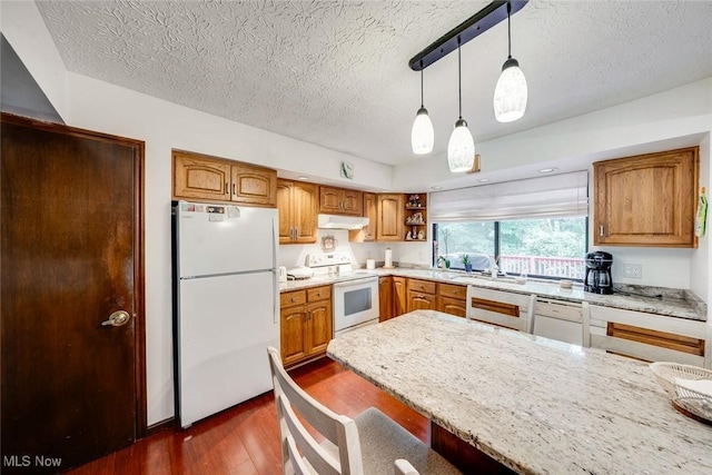 kitchen featuring white appliances, a textured ceiling, hanging light fixtures, dark hardwood / wood-style flooring, and light stone counters