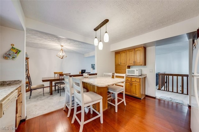 kitchen featuring decorative light fixtures, dark wood-type flooring, white appliances, and a kitchen island