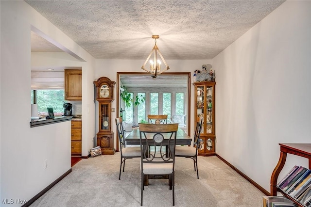 dining space featuring light carpet, a healthy amount of sunlight, a textured ceiling, and an inviting chandelier