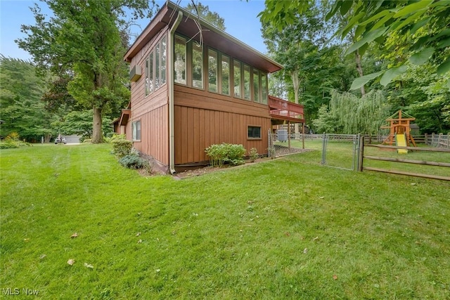 exterior space featuring a playground, a yard, and a sunroom