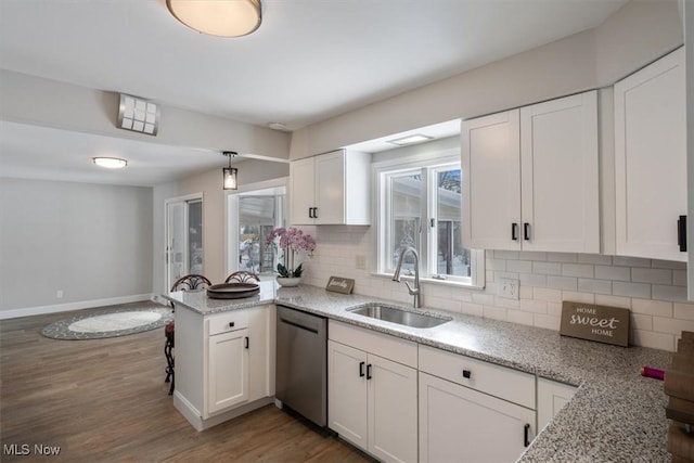 kitchen featuring white cabinetry, tasteful backsplash, sink, kitchen peninsula, and stainless steel dishwasher