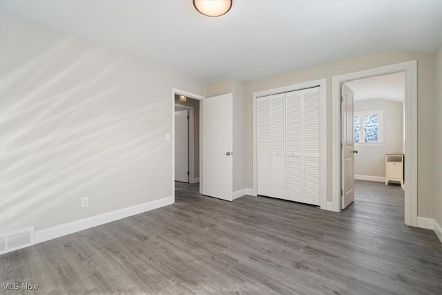 unfurnished bedroom with dark wood-type flooring, a closet, and lofted ceiling