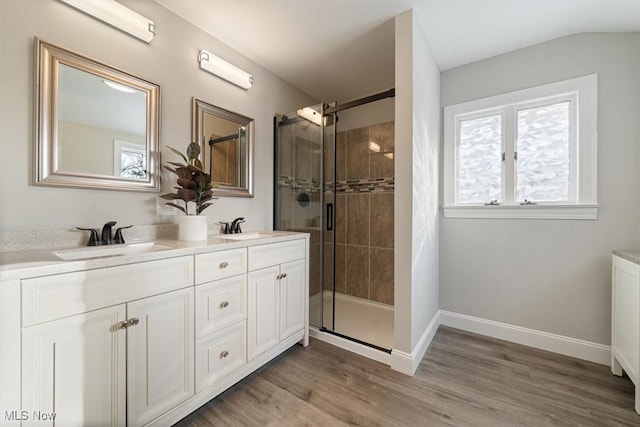 bathroom with hardwood / wood-style floors, walk in shower, lofted ceiling, and vanity