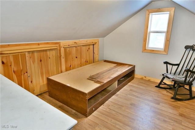 additional living space with wood-type flooring and vaulted ceiling