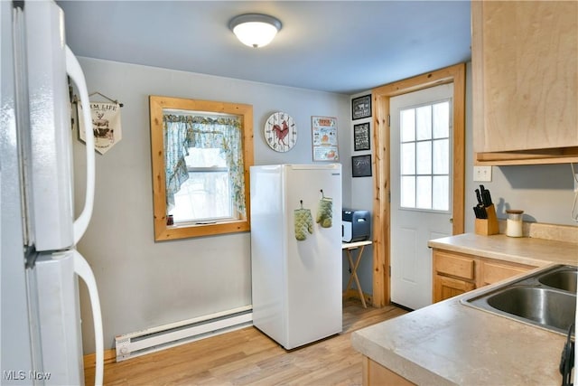 kitchen with a baseboard heating unit, light hardwood / wood-style flooring, light brown cabinets, and white refrigerator