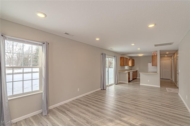 unfurnished living room with light hardwood / wood-style floors and a textured ceiling