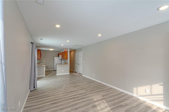 unfurnished living room featuring sink and light hardwood / wood-style flooring