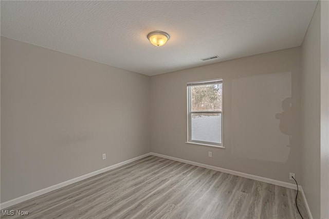 spare room featuring a textured ceiling and light hardwood / wood-style flooring