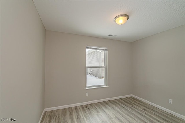 unfurnished room with light hardwood / wood-style floors and a textured ceiling