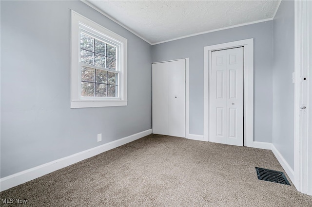 unfurnished bedroom with a textured ceiling, multiple closets, and carpet flooring