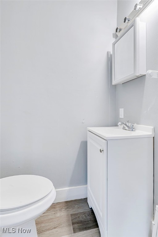 bathroom with wood-type flooring, toilet, and vanity