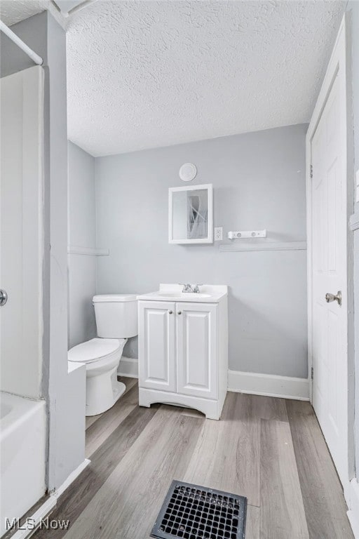 bathroom with hardwood / wood-style floors, toilet, vanity, and a textured ceiling