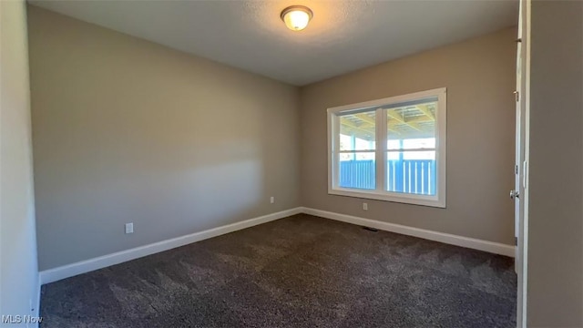 spare room featuring dark colored carpet