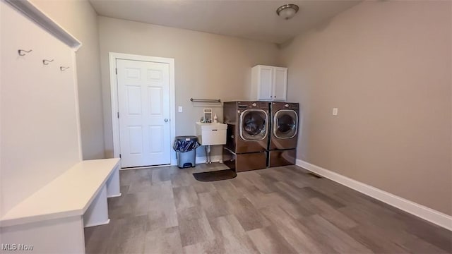 laundry room featuring cabinets, light hardwood / wood-style flooring, sink, and washing machine and dryer