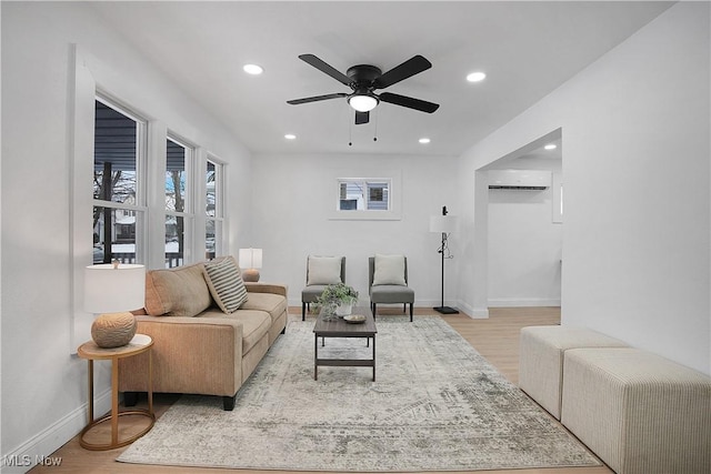 living room with light wood-type flooring, an AC wall unit, and ceiling fan