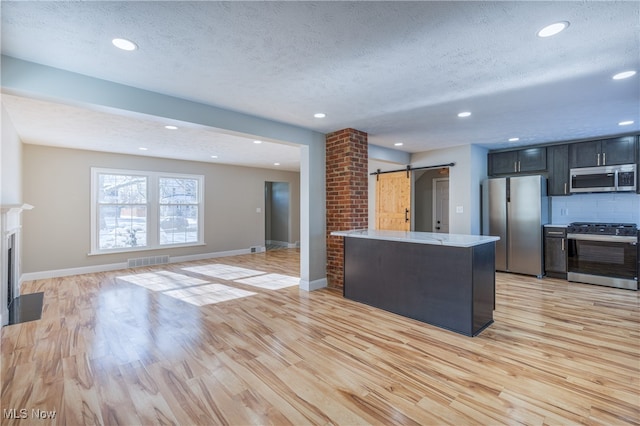 kitchen with stainless steel appliances, a barn door, a textured ceiling, and tasteful backsplash