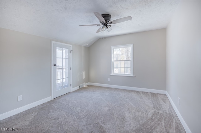 unfurnished room featuring a textured ceiling, carpet flooring, lofted ceiling, and ceiling fan