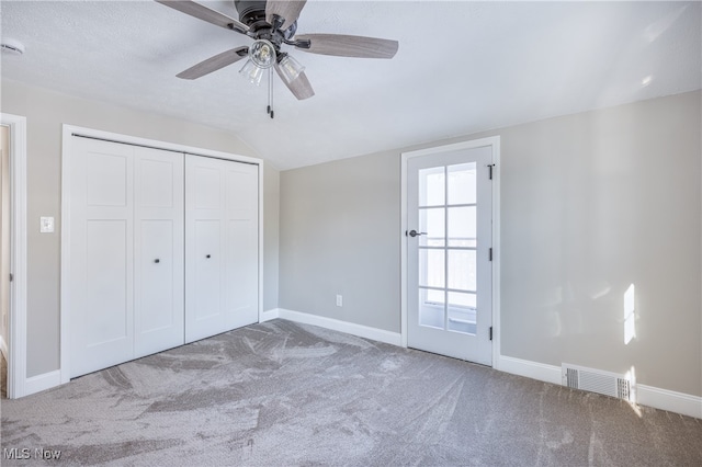 unfurnished bedroom featuring lofted ceiling, carpet flooring, a closet, and ceiling fan