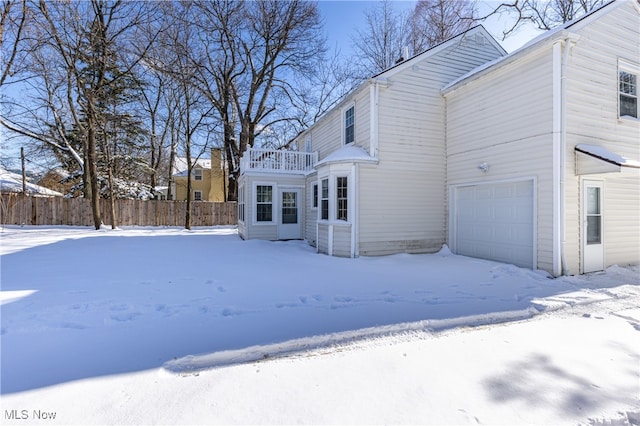 snow covered property with a balcony and a garage