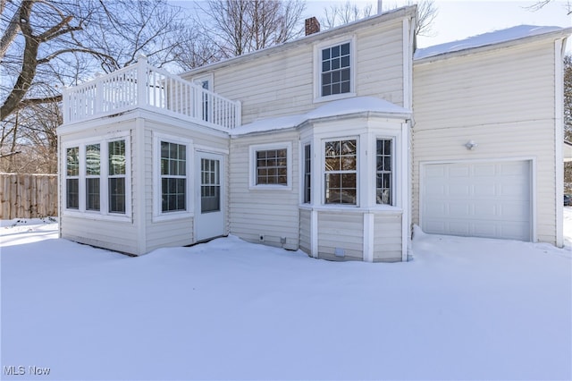 snow covered property featuring a balcony and a garage