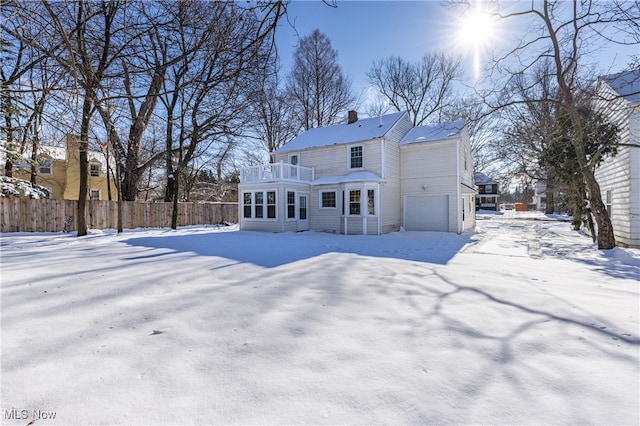 snow covered property with a balcony and a garage