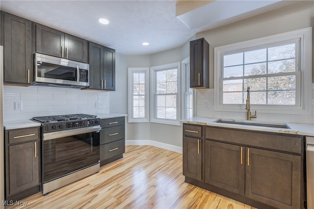 kitchen with sink, appliances with stainless steel finishes, light hardwood / wood-style flooring, and plenty of natural light