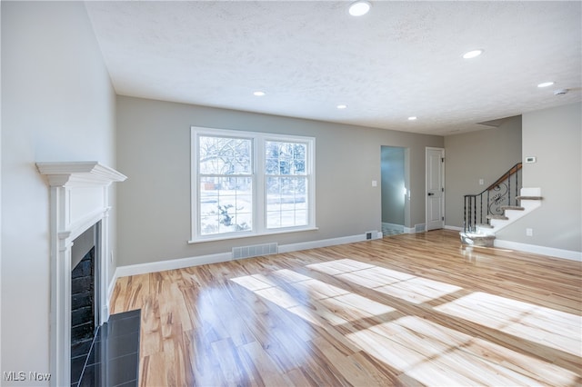 unfurnished living room featuring light hardwood / wood-style floors and a textured ceiling